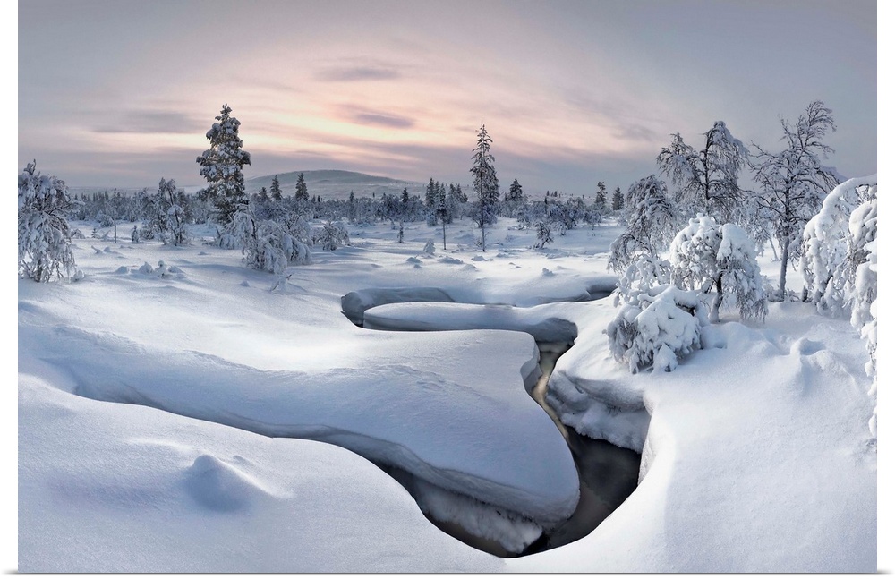 A river cuts a curved path through a landscape with a think blanket of snow in Finland.