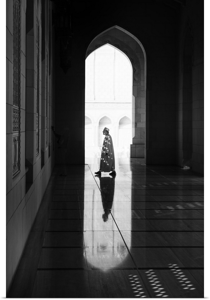 A photograph of a man and architectural interior casting reflections on the floor.