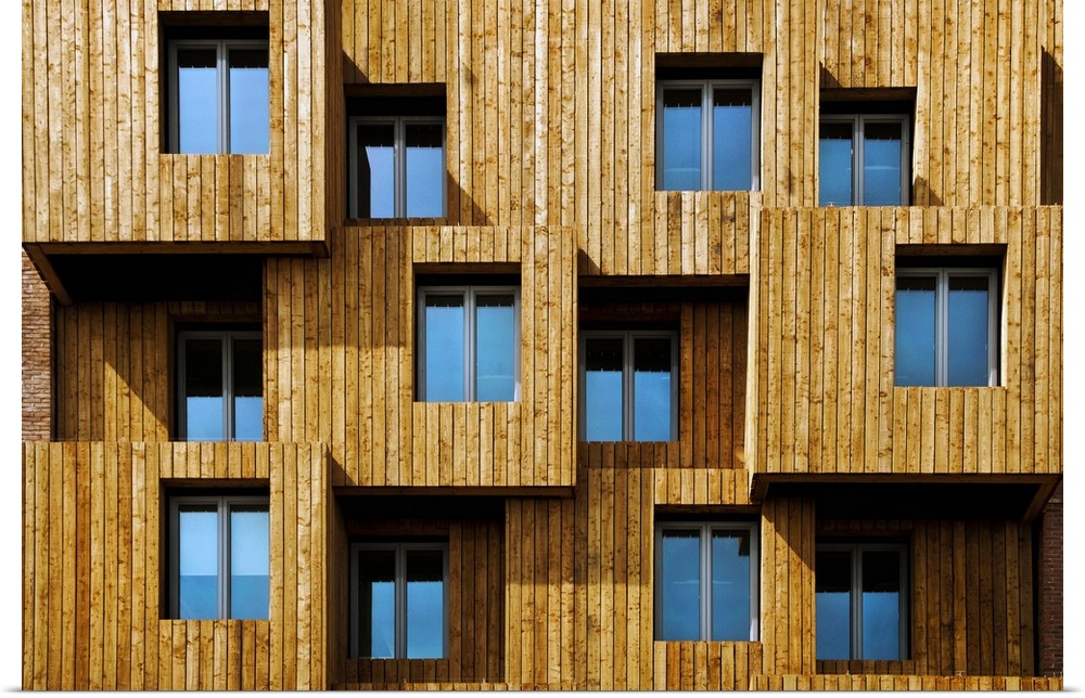 Architectural photograph of a unique wooden facade  with windows reflecting the blue sky, Wales.
