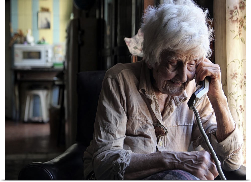 Portrait of an elderly woman talking on a corded telephone.