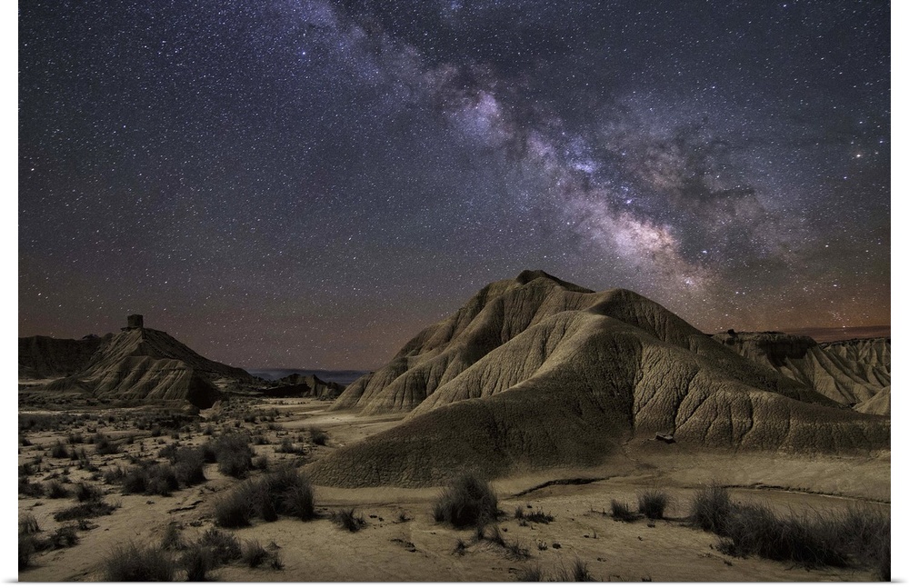 The Milky Way galaxy illuminated over a rocky desert landscape.