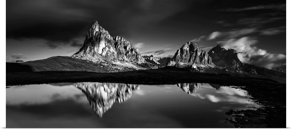 Black and white panoramic landscape photograph of the Dolomites, Italy with reflections on the lake.