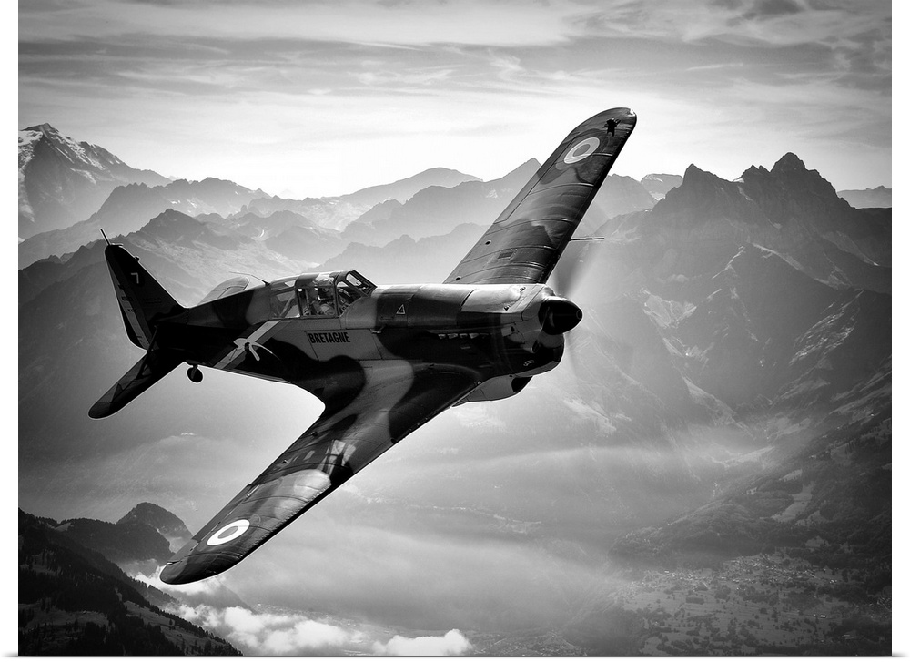 Black and white image of a vintage airplane flying over the Swiss Alps.