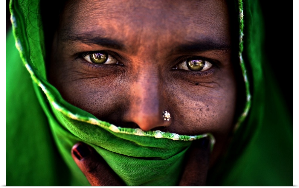 A portrait of a woman with most of her face covered by a green wrap.