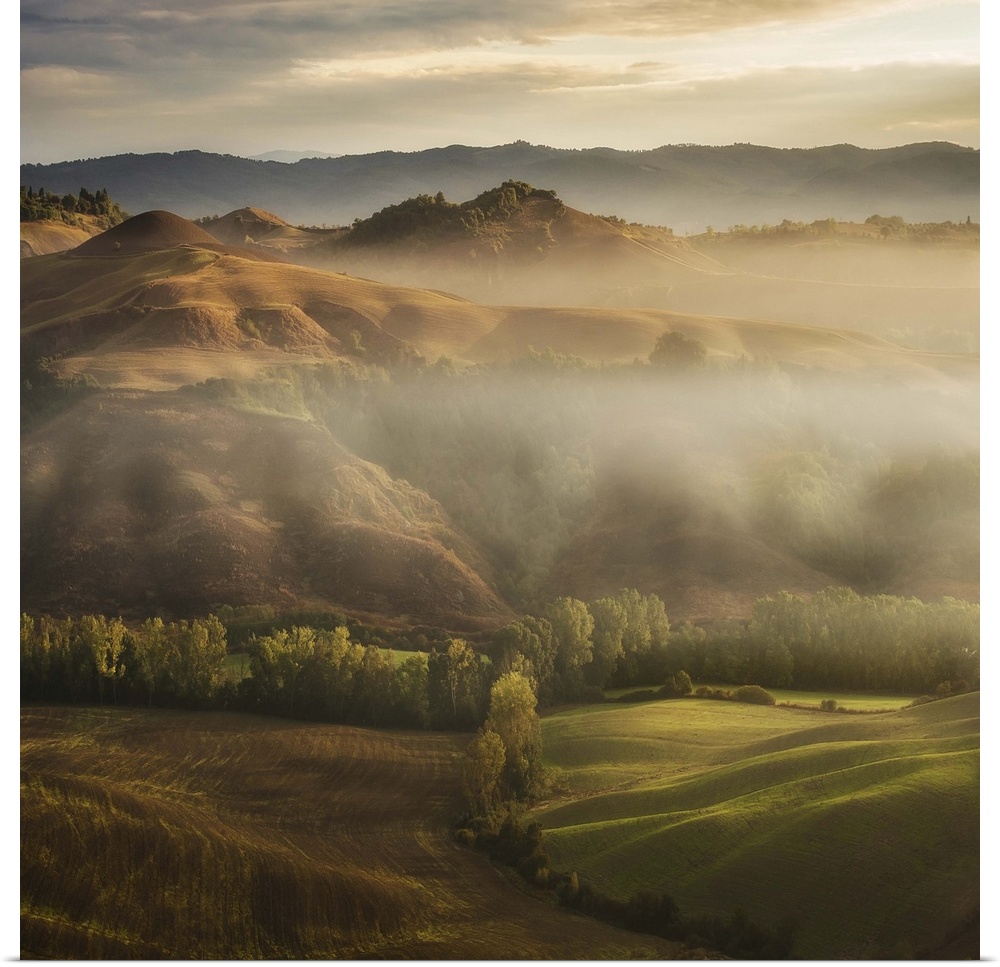 A Tuscan landscape with fog laying in the deep sections of the valley.