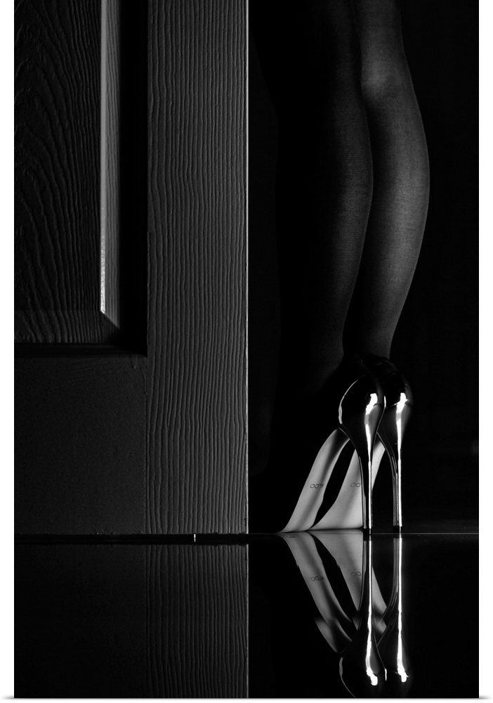 Woman wearing a pair of very tall high heel shoes standing next to a door.