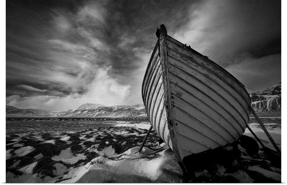 A black and white photograph of a row boat on the shore of an Icelandic beach.