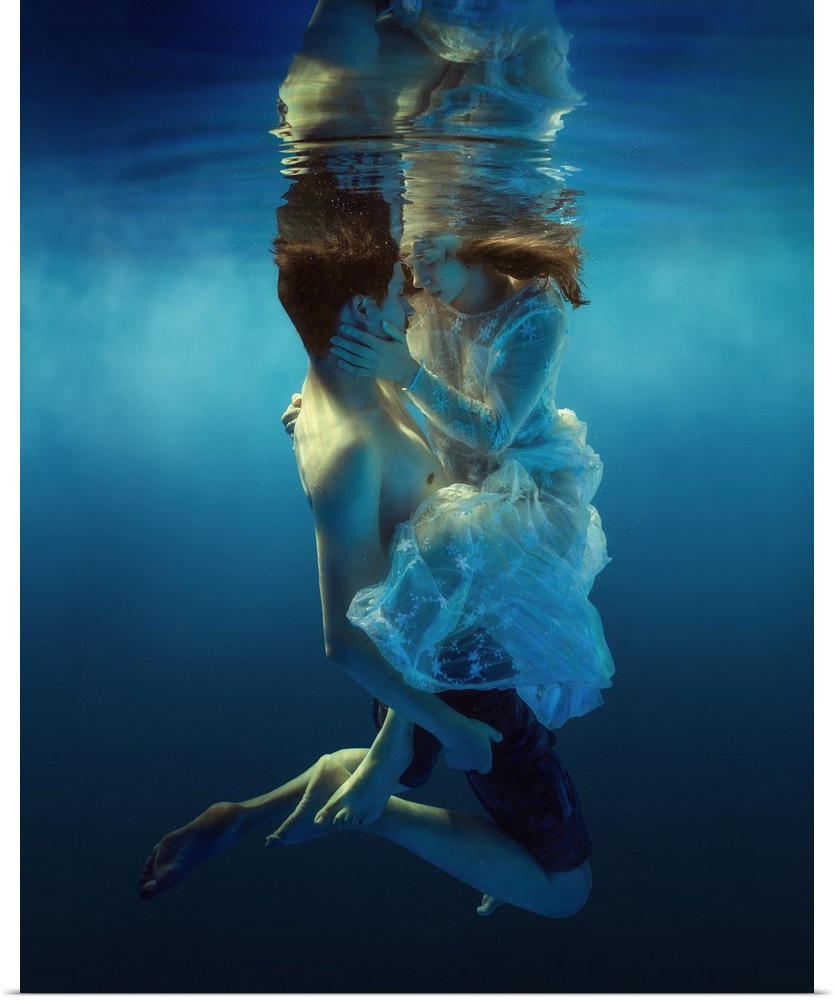 Underwater portrait of a man and woman holding each other, about to kiss.