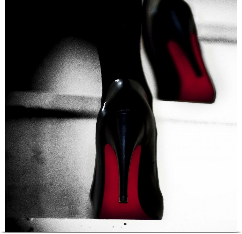 Close up view of two black high heels with red soles walking up steps.