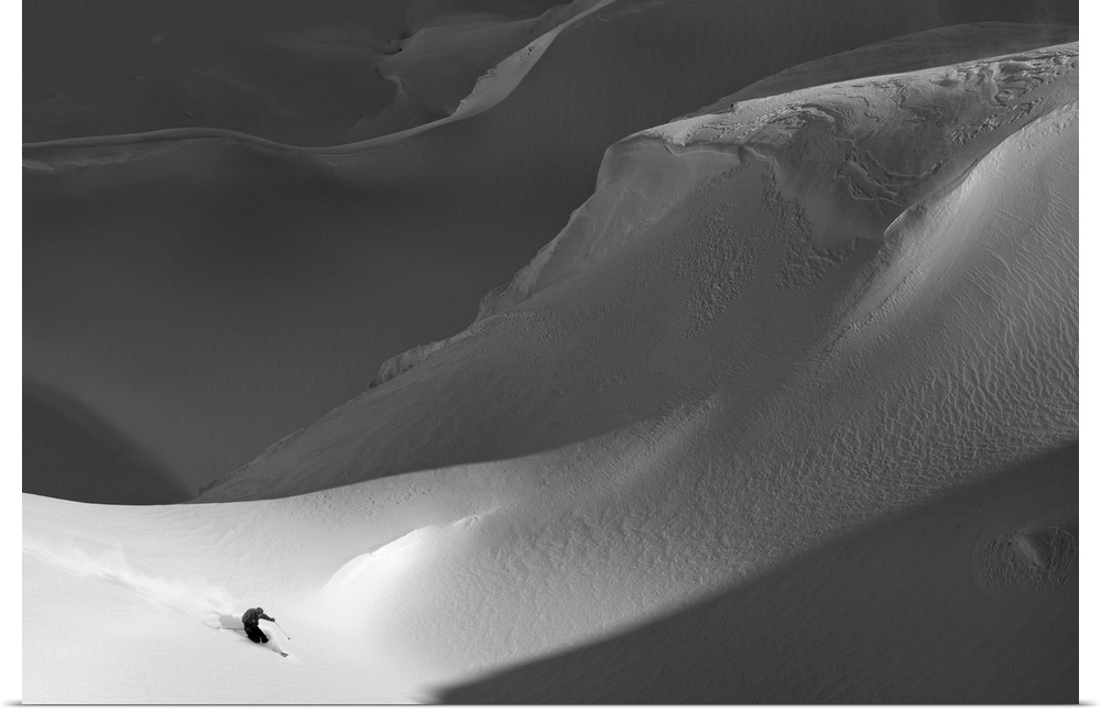A skier on the side of a treacherous snowy mountain.
