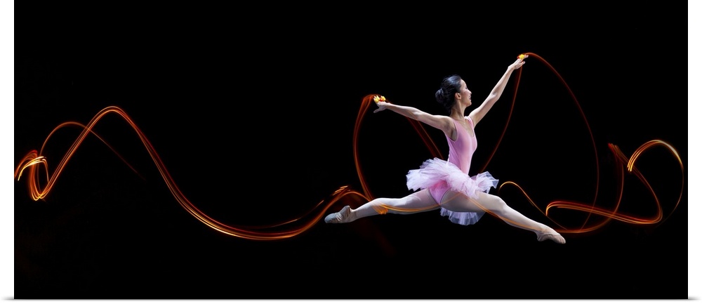 A ballerina leaping, with light trails left in the air from her movements.