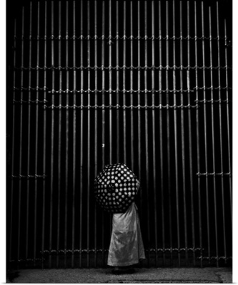 Person with a spotted umbrella at an iron gate