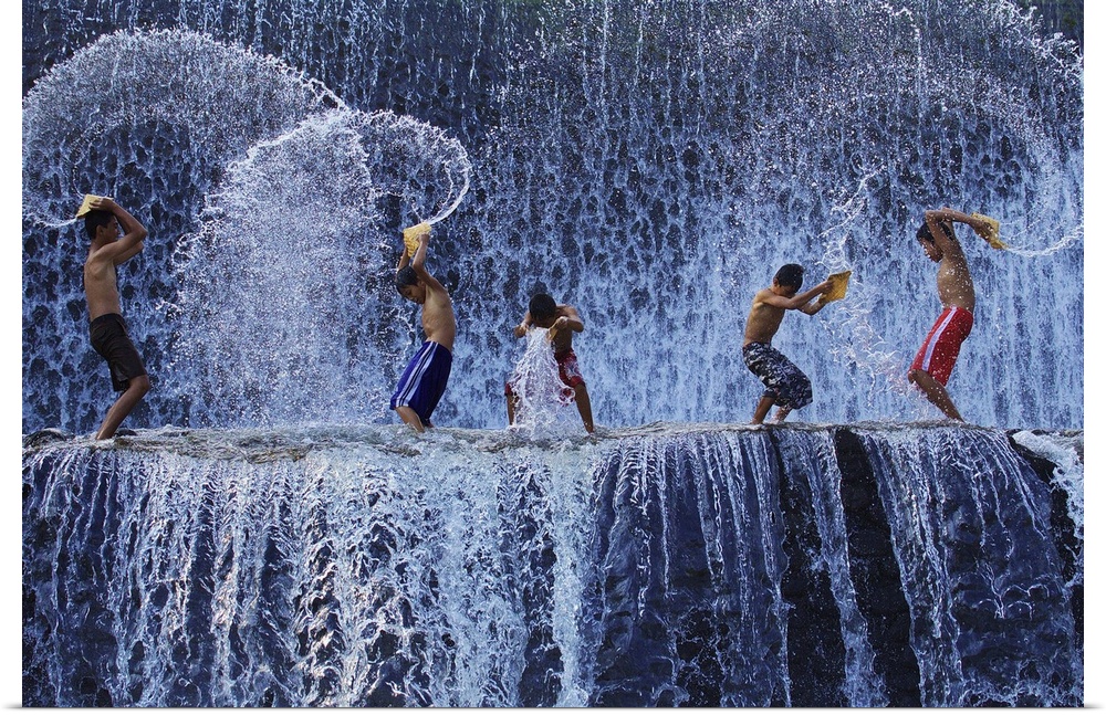 A group of children play in a waterfall, creating spiraling forms as they splash in the water.