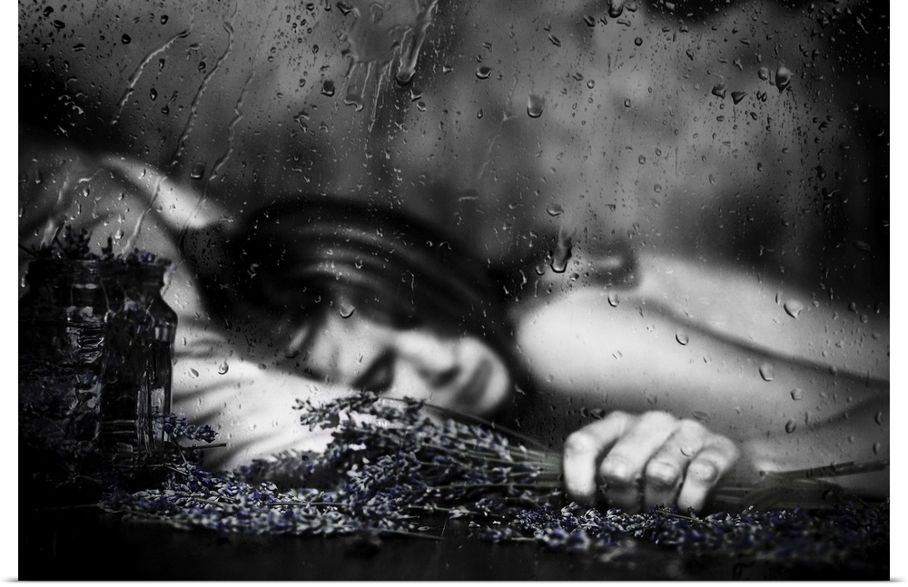 Black and white image of a woman laying down with falling raindrops.