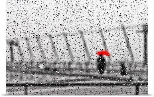 An out of focus image of a figure holding a bright red umbrella, seen through a window covered in raindrops.
