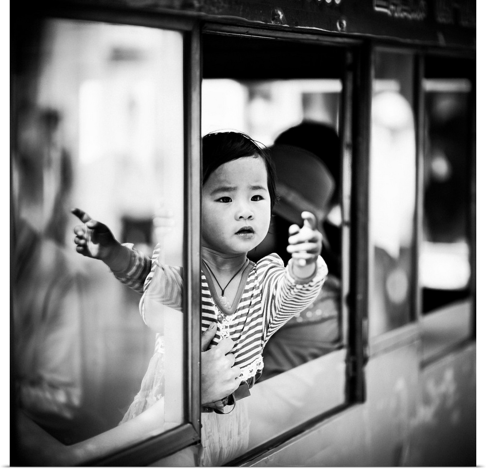 A child reaches out from the window of a train as their parent holds them back.
