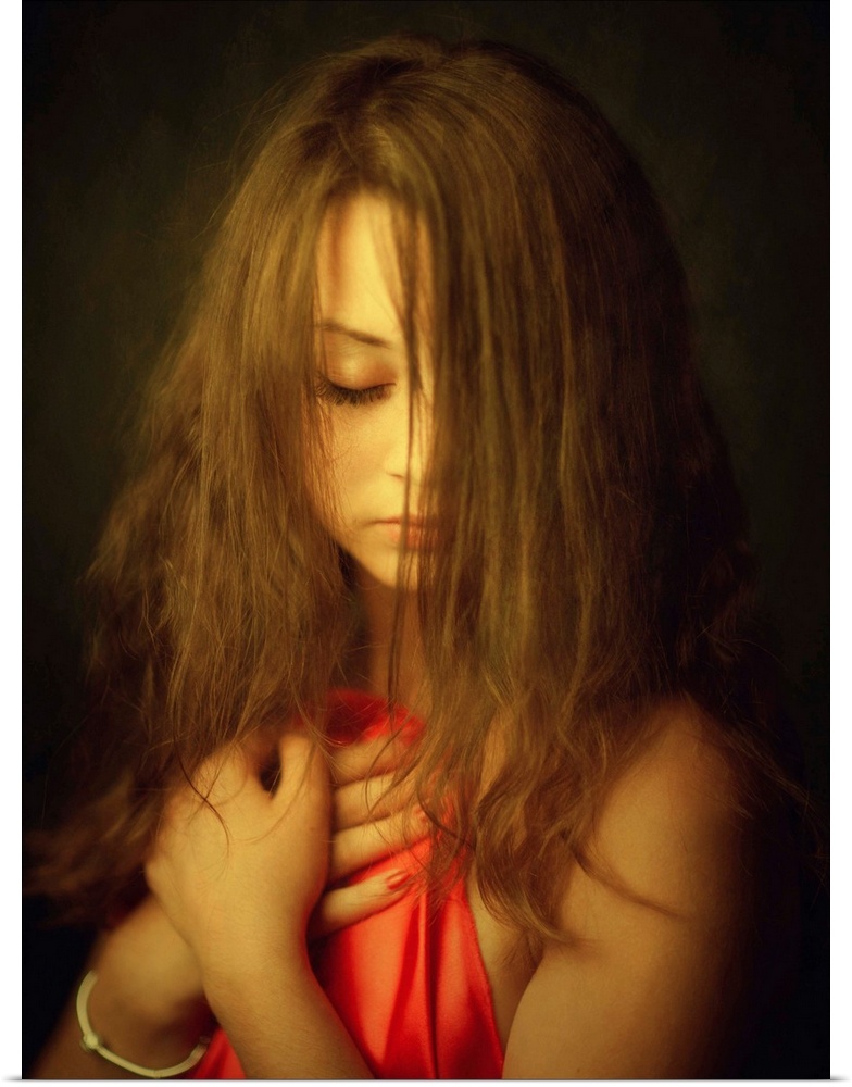 A woman with her hair in her face holding up a red cloth to her chest.