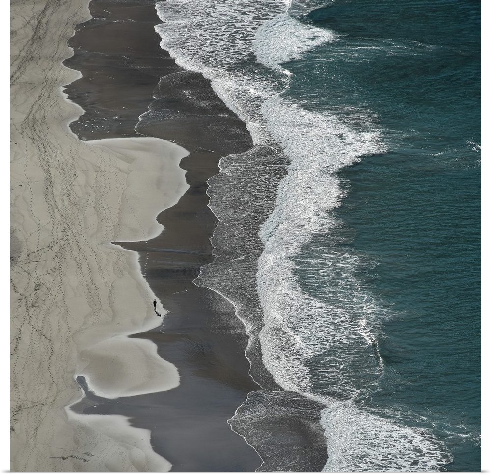 Aerial photograph of the ocean shore with tan, gray, white, and blue vertical separations.