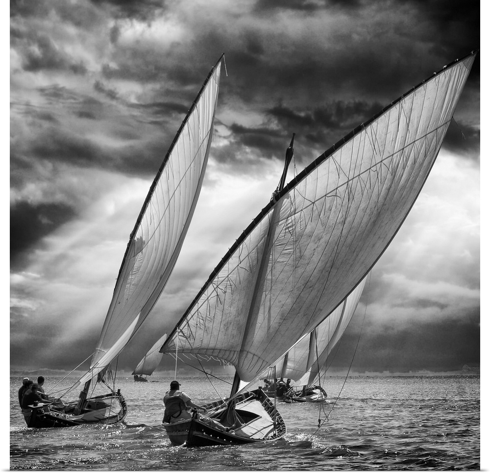 Black and white image of a fleet of sailboats leaning in the wind under stormy skies.
