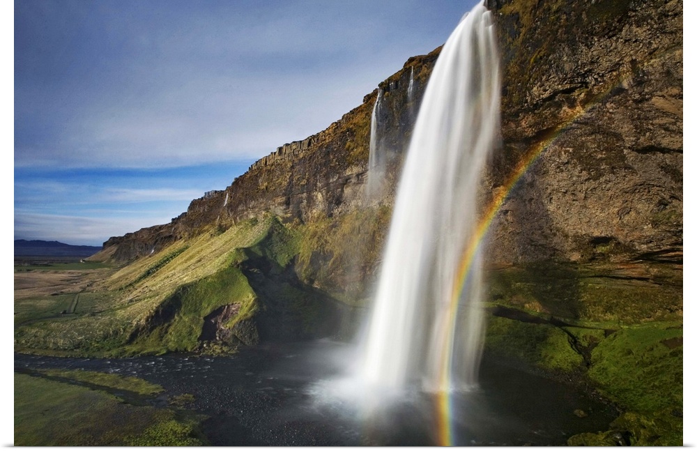 A waterfall in a cliff with a rainbow, Seljalandsfoss, Iceland.