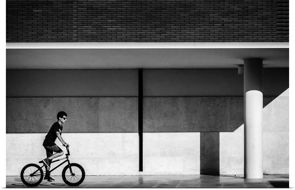 a black and white photograph of a boy riding a bike.