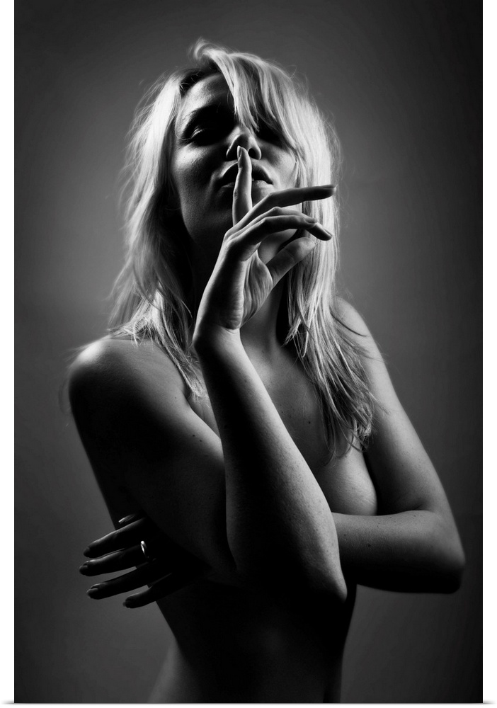 Portrait of a beautiful woman holding a finger up to her mouth in silence.
