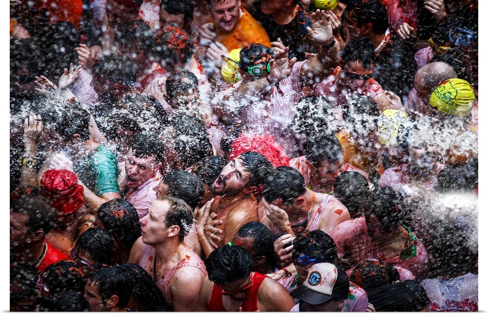 A large group of men in the street being sprayed with water.