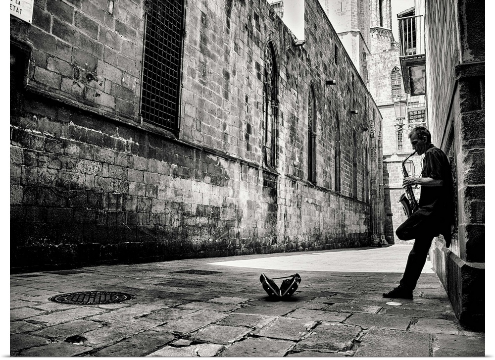 A black and white photograph of a person playing a saxophone in an alley.