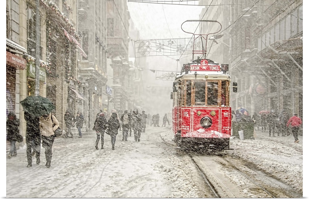 A snowstorm raining down on a city with a red street car in the street.