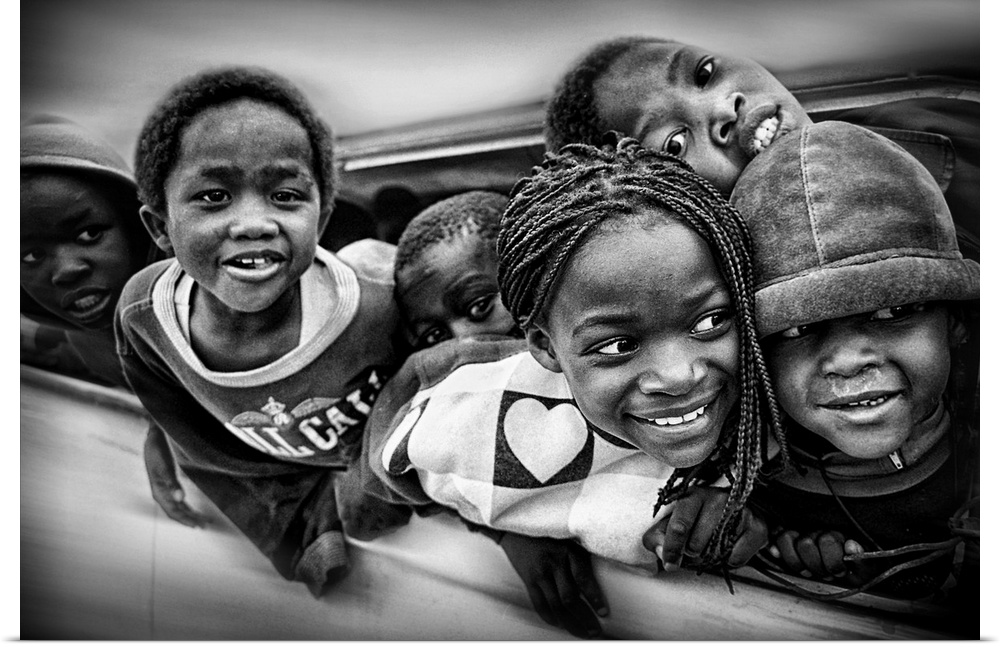 A group of young African American children lean out of the window of a car.