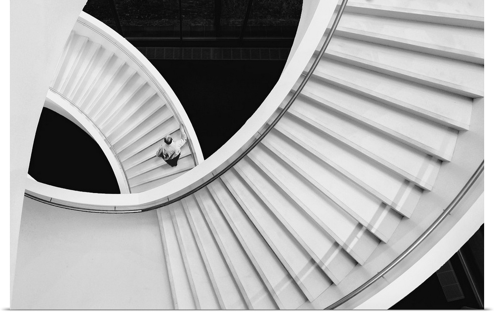 Person walking up a spiraling staircase, seen from above.