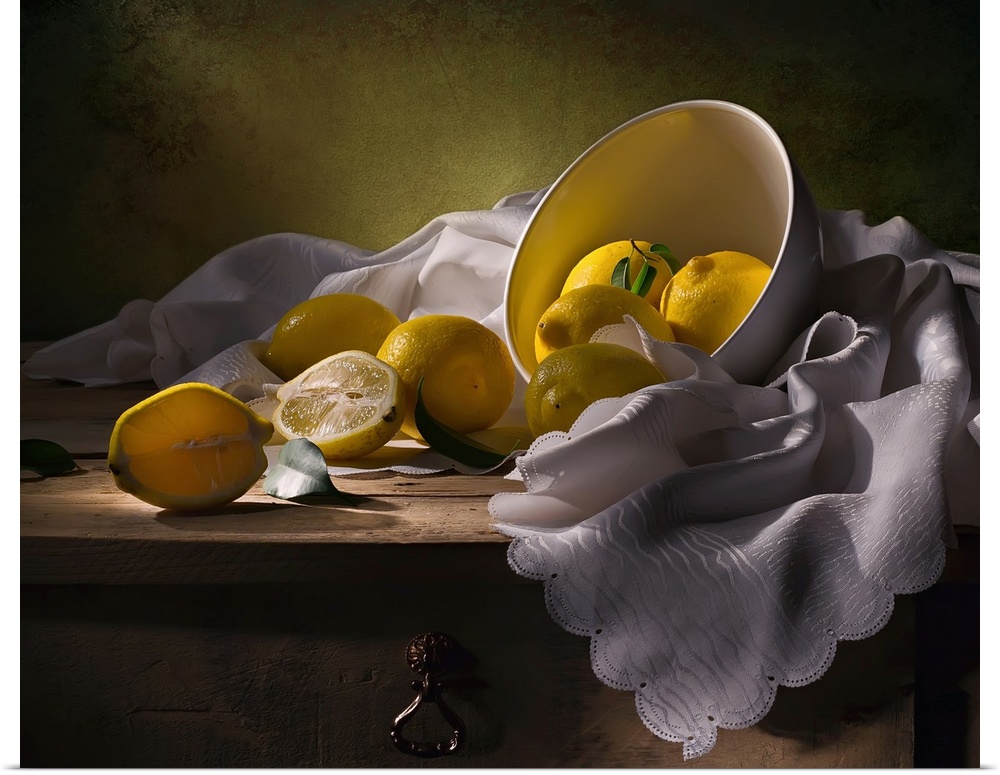 A bowl of lemons on a white cloth, one split in half.