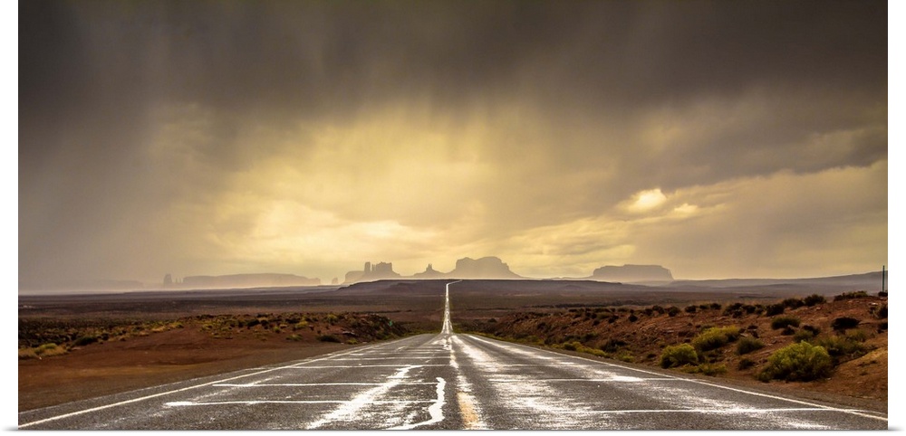 Road leading towards the rock formations in Monument Valley under a stormy sky.