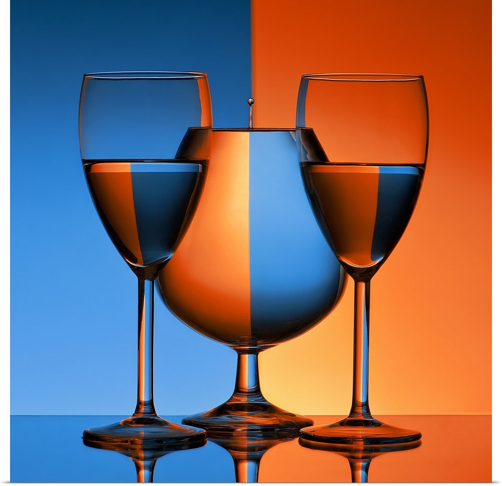 Conceptual image of three glasses reflecting mirror images of a blue and orange background.