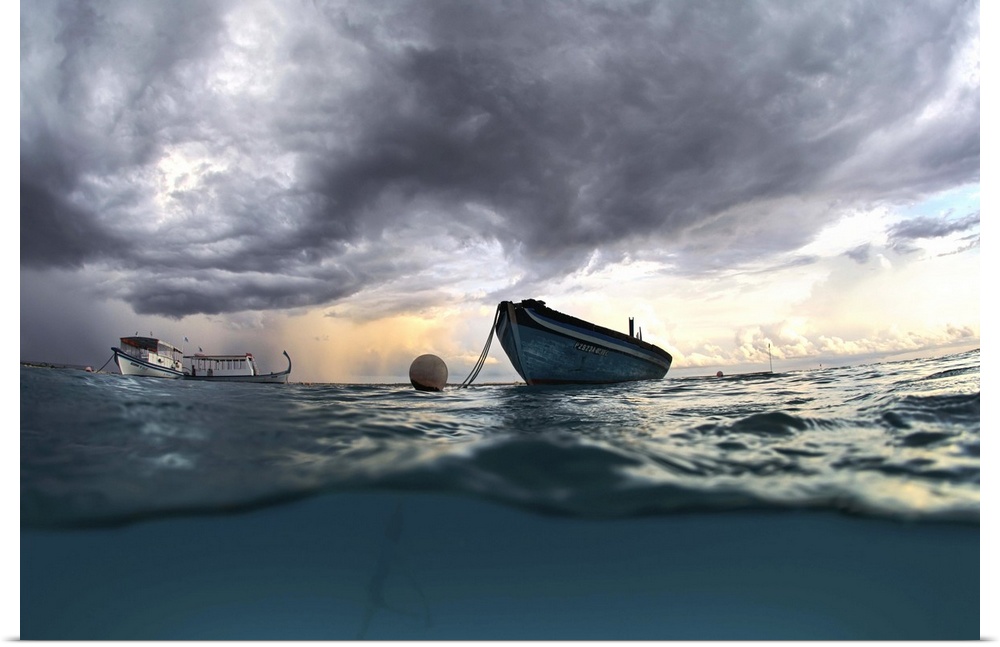 View from the surface of the ocean of a boat at sea with dark clouds in the sky.