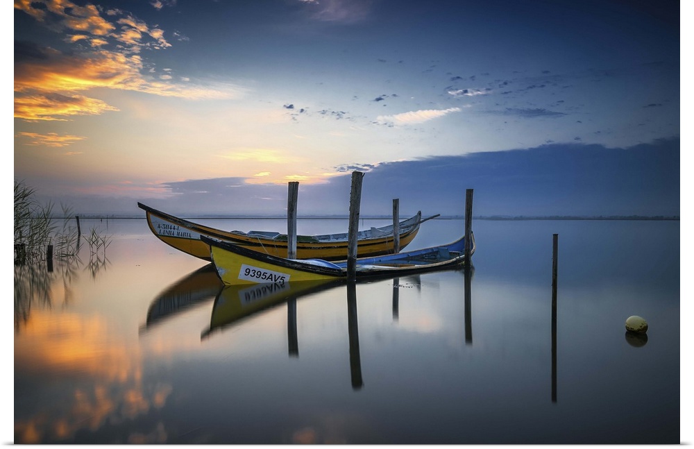 Photograph of two yellow boats docked on a calm lake at sunset.