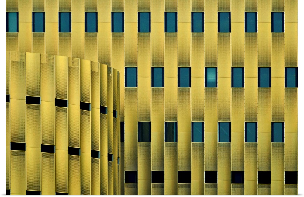 Facade of a yellow building with repeating blue windows, forming an abstract pattern.