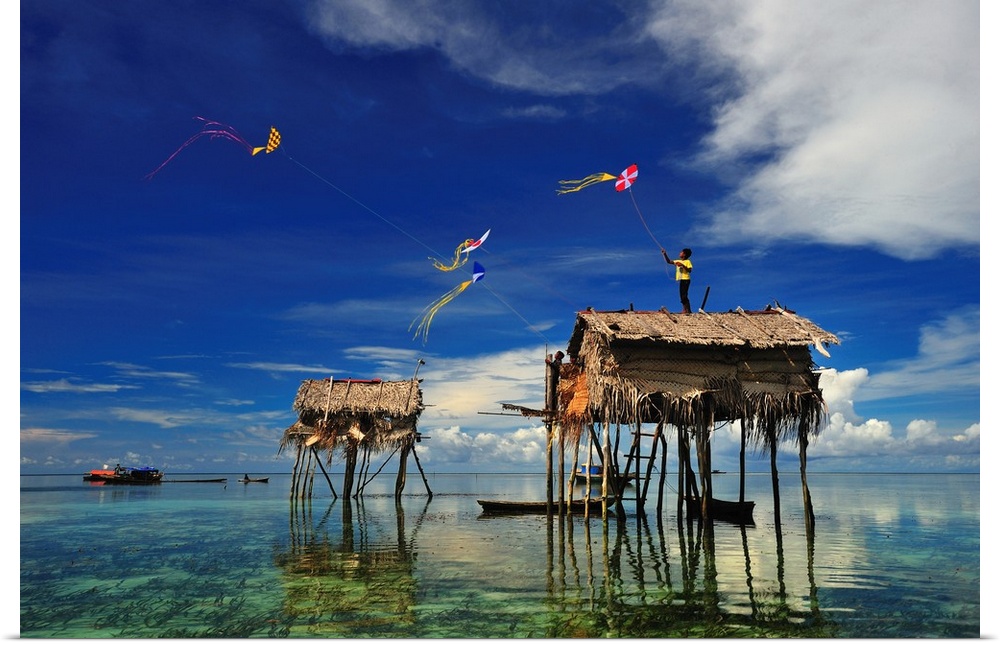 Kites flying over a group of houses on stilts in the ocean, Sabah, Malaysia.
