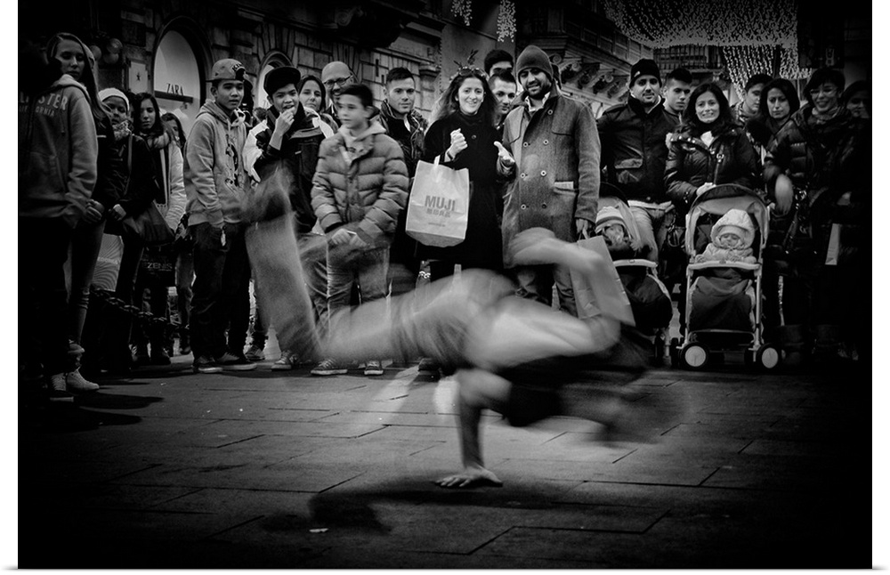 A crowd of people gathering to watch a breakdancer perform in the street.