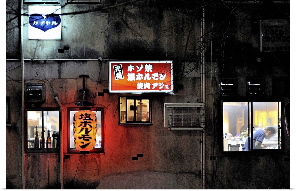 A wall with lit up street signs and windows on the side of a building in Kyoto, Japan.