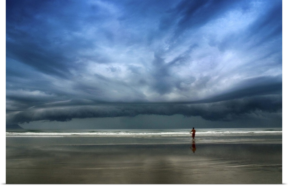 Adventurous surfer heads into the water, undeterred by the approaching stormclouds.