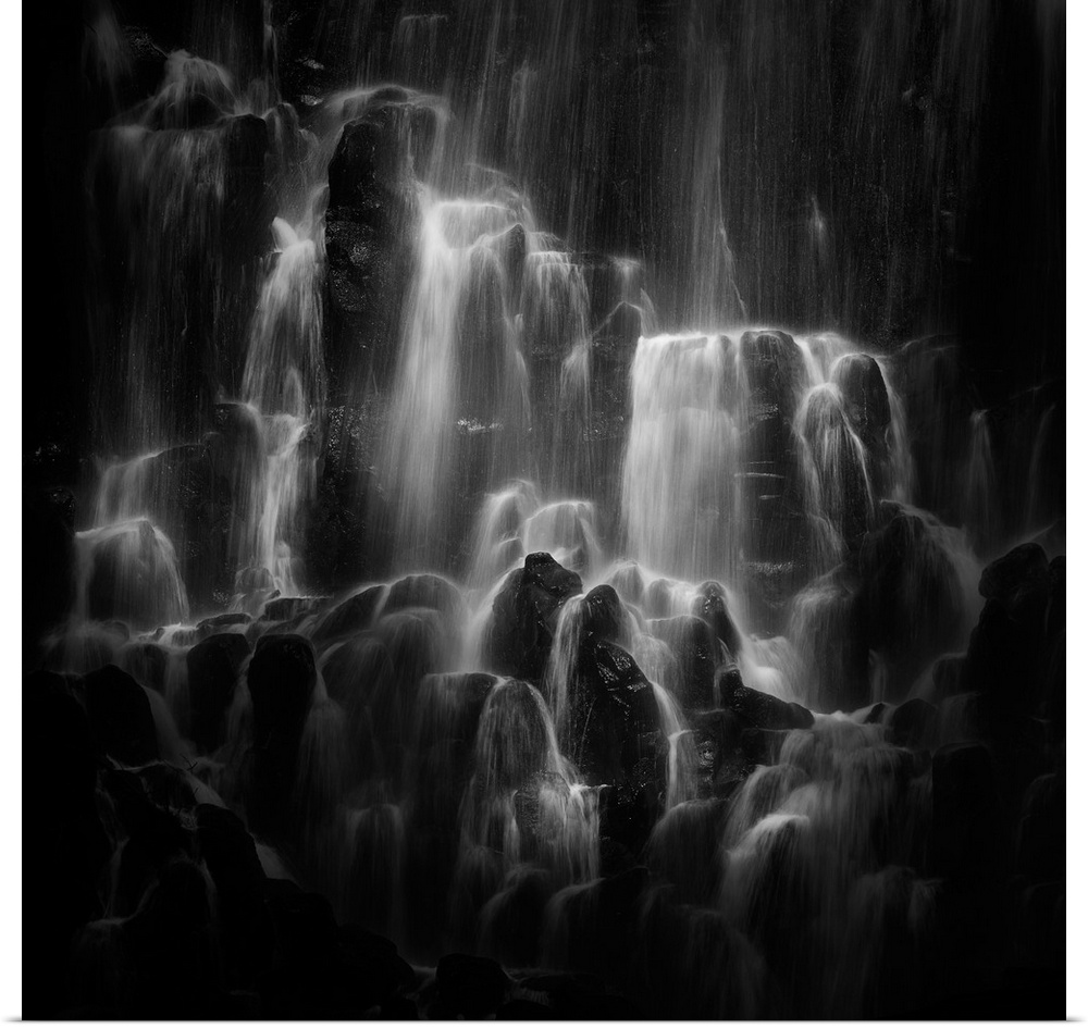 Water cascading down over top of jagged rocks.