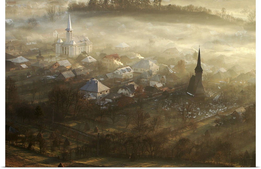 Morning view of a village with the tops of buildings rising out of the mist.