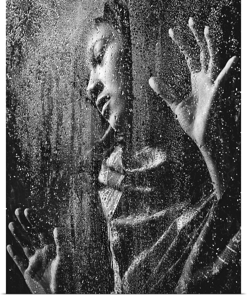 A woman pressing her hands against a window covered in raindrops.
