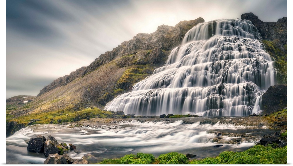 A giant Icelandic waterfall with motion blurred clouds above.