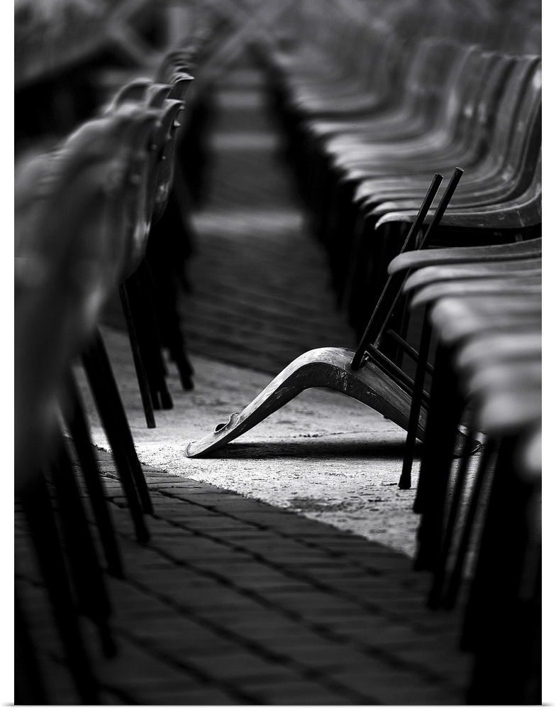 Rows of identical chairs with one that has fallen out of line.