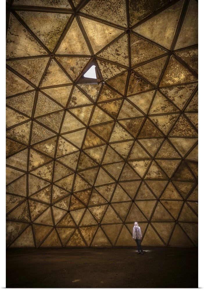 A person standing in a spotlight created by one open panel in a geodesic dome structure.