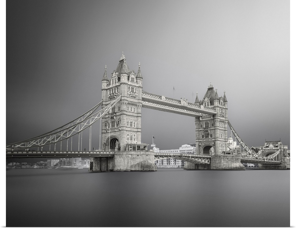 Black and white photograph of Tower Bridge in London with silky, calm water below.