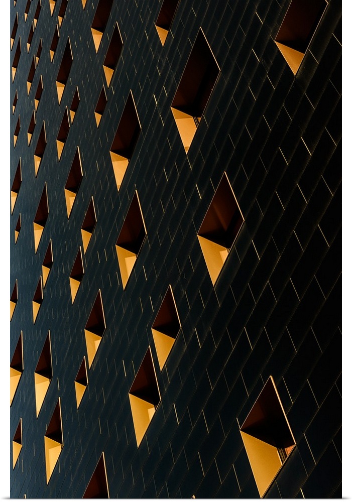 Architectural abstract photograph of a building facade with black rectangular tiles and yellow window.