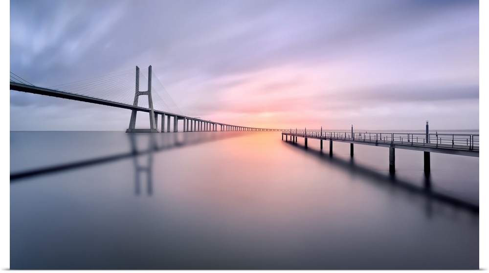 A serene view of a bridge curving into a bend in the distance with a pier to the side jetting out into the water.